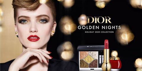 Eine Frau mit auffälligem Make-up und rotem Lippenstift posiert mit der Dior Golden Nights Holiday 2020-Kollektion, die Lidschatten, Lippenstift und Nagellack vor einem Hintergrund aus goldenen Lichtern umfasst.