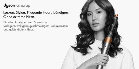 Eine Frau mit langem, welligem Haar hält einen Dyson Airwrap Styler in der Hand. Der deutsche Text wirbt für die Fähigkeit des Produkts, Haare ohne extreme Hitze zu locken und zu stylen. Das Gerät ist ein schlanker Metallzylinder mit einem dunklen Zylinderaufsatz.