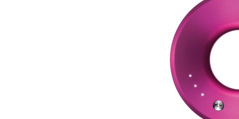 Nahaufnahme eines rosa, teilweise sichtbaren runden Objekts mit abgerundeter Kante vor weißem Hintergrund. Es weist drei kleine weiße Punkte und ein metallisches Detail auf.