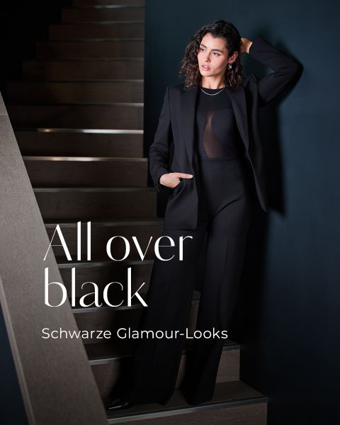Eine Frau in elegantem, schwarzem Outfit lehnt an einer dunklen Wand neben einer Treppe. Ein großer Text lautet: "Ganz in Schwarz", und darunter steht in kleinerer Schrift: "Schwarze Glamour-Looks".