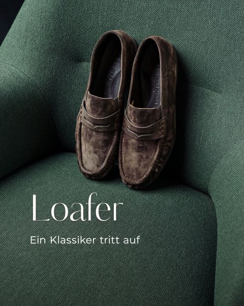 Wildleder-Loafer auf einem grünen Stoffsessel. Der Text lautet: „Loafer. Ein Klassiker tritt auf.“.