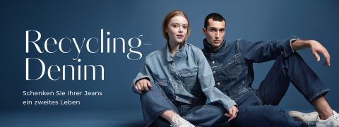 Eine Frau und ein Mann sitzen vor einem dunkelblauen Hintergrund und tragen Jeans-Outfits. Der Text lautet: „Recycling-Denim. Schenken Sie Ihrer Jeans ein zweites Leben.“ Beide zeigen eine entspannte Pose.