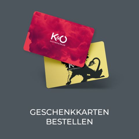 Zwei Geschenkkarten auf grauem Hintergrund. Die obere Karte ist rot und trägt das Logo „K&Ö Kastner & Öhler“. Die untere Karte ist gelb und zeigt die Silhouette eines Löwen. Darunter steht der Text „Geschenkkarten bestellen“.