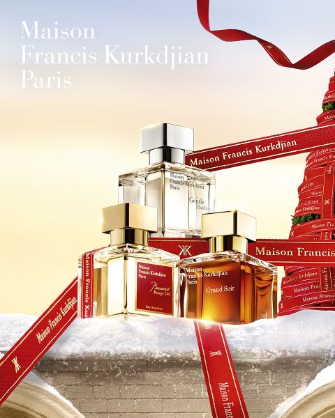 Drei Parfümflakons von Maison Francis Kurkdjian Paris stehen auf einer verschneiten Fläche, umgeben von roten Bändern von Maison Francis Kurkdjian, vor einem festlichen Hintergrund und mit sanfter Beleuchtung.