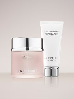 Zwei Hautpflegeprodukte von La Prairie Switzerland: ein rosa Tiegel mit „Cashmere Body Cream“ und eine weiße Tube mit „Cellular Hand Cream“, nebeneinander.