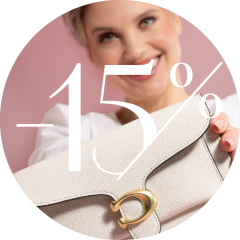 Eine lächelnde Person hält eine helle, strukturierte Handtasche mit goldenem Verschluss. Der weiße Text auf dem Bild lautet „-15 %“. Der Hintergrund ist zartrosa.
