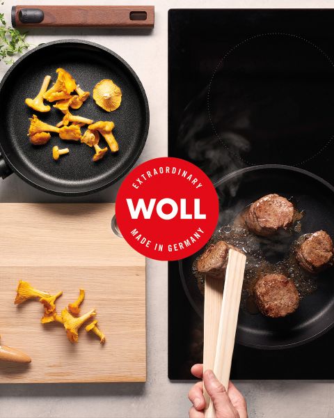 Draufsicht auf Pilze in einer Pfanne, ein Steak, das auf dem Herd brät, und eine Hand, die eine Zange hält, mit einem roten „WOLL Made in Germany“-Logo in der Mitte.