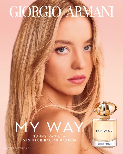 Eine lächelnde Frau in einem schwarzen One-Shoulder-Kleid steht vor einem kräftigen roten Hintergrund mit "GIORGIO ARMANI" über ihr. Zwei Armani-Parfümflaschen "Sì" sind unten mit goldener und schwarzer Schrift abgebildet.