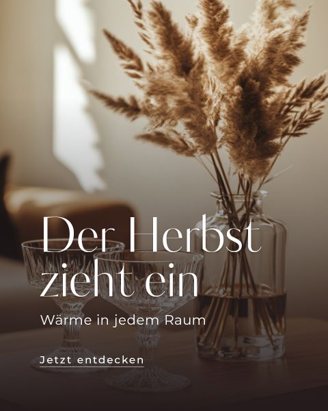 Eine Person nimmt eine frisch gebackene Pizza aus einem modernen Outdoor-Pizzaofen auf einen Holztisch, der mit Tellern, Weingläsern und frischen Zutaten gedeckt ist. Der Text lautet: „Sommer-Highlights für Zuhause. Jetzt entdecken.“.