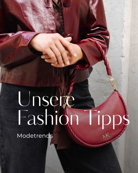 Eine Person in einer glänzenden burgunderroten Lederjacke hält eine passende MK-Handtasche. Der Text auf dem Bild lautet: "Unsere Fashion Tipps. Modetrends 2025.
