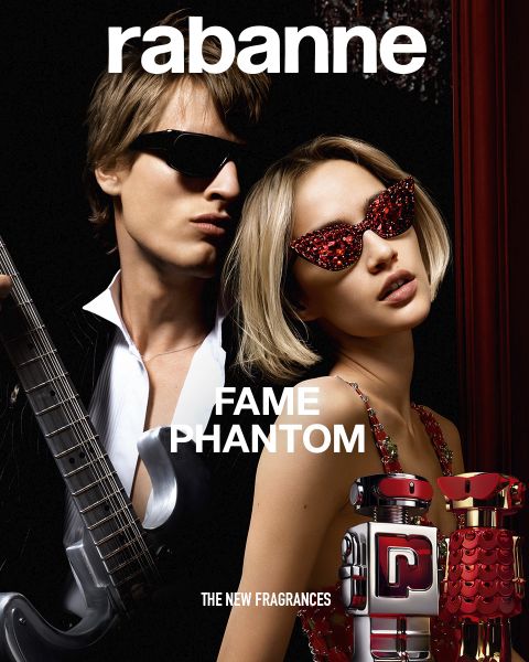 Zwei Flaschen des Parfüms Rabanne Olympéa ABSOLU, eine schwarze und eine rosa, sind vor einer blühenden weißen Blume auf dunklem Hintergrund ausgestellt. Der Text lautet: „Rabanne OLYMPÉA ABSOLU – DER NEUE DUFT.“.