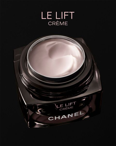 Eine Frau mit strahlender Haut posiert neben zwei Chanel Les Beiges Concealer-Produkten und trägt Silberschmuck vor einem zartbeigen Hintergrund.