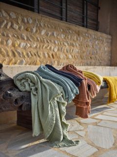 Vier olivgrüne, rechteckige Kissen mit dezentem Rüschenrand sind in zwei Reihen vor einem Hintergrund mit grau-weißem Farbverlauf angeordnet.