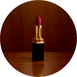 Ein rosafarbener Lippenstift in einer silbernen Hülse liegt auf einer weißen Fläche, hinter der rosa Lippenstift verschmiert ist.