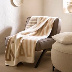 Ein moderner, runder Stuhl mit einem weichen Kissen steht neben durchsichtigen, gemusterten Vorhängen neben einem Fenster. Ein passendes Kissen liegt auf dem Holzboden und sanftes Licht fällt durch das Fenster und schafft eine gemütliche Atmosphäre.