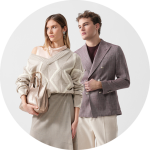 Zwei Personen stehen nebeneinander; die eine trägt eine braune Jacke, die andere eine Sonnenbrille und eine hellbraune Jacke über einem rosa Kleid mit kreisförmigen Mustern.