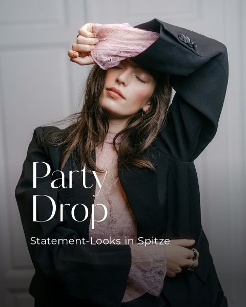 Eine Person, die einen schwarzen Blazer über einem rosa Spitzenoberteil trägt, auf dem die Aufschriften „It-Piece: Spitze“ und „Zarte Details & große Wirkung“ zu lesen sind.