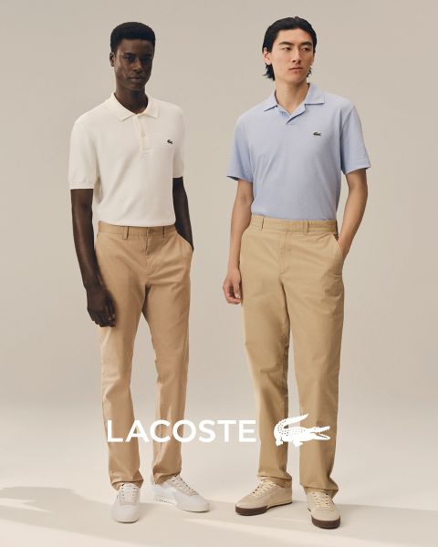 Vier Models posieren im Freien in Lacoste-Outfits vor einem blauen Himmel. Von links nach rechts: eine Person im Trenchcoat, eine Person in Pullover und Hose, eine Person in Weste und Rock und eine Person im Trainingsanzug. Das Lacoste-Logo befindet sich unten.