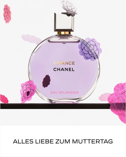 Eine lächelnde Frau in rosafarbener Jacke und schwarzem Rock springt neben einer großen Flasche des Parfums CHANEL Chance Eau Splendide auf weißem Hintergrund.