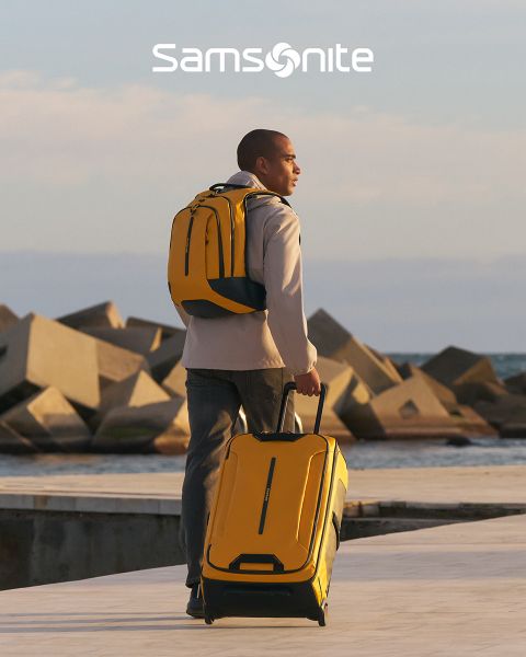 Hellgrüner Samsonite-Koffer mit strukturiertem Muster und vier Rollen. Der Griff ist ausziehbar. Das große „Samsonite“-Logo ist quer über den Koffer gebreitet. Der Hintergrund hat ein wellenförmiges grün-weißes Design.