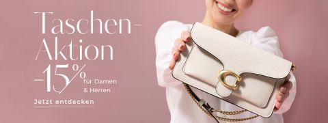 Eine lächelnde Frau in weißer Bluse hält eine beige Designerhandtasche mit goldenem Verschluss in die Kamera. Ein deutscher Text kündigt 15 % Rabatt auf Taschen für Damen und Herren an. Rosa Hintergrund.