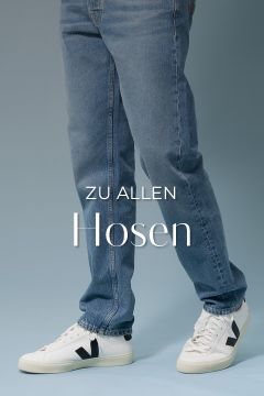 Eine Person in hellblauen Jeans und weißen Turnschuhen steht vor einem schlichten blauen Hintergrund. Der Text „ZU ALLEN Hosen“ ist über das Bild gelegt.