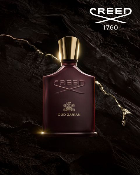 Ein dunkelkastanienbrauner Flakon des Parfums Creed Oud Zarian mit einer goldenen Kappe steht vor einem strukturierten, dunklen Hintergrund. Goldene Flüssigkeit wirbelt um den Flakon. Das Creed-Logo und "1760" befinden sich in der oberen rechten Ecke.