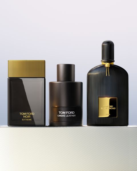 Drei Parfümflakons von Tom Ford - Noir Extreme, Ombré Leather und Black Orchid - stehen nebeneinander auf einer strukturierten weißen Oberfläche mit einem hellen Hintergrund mit Farbverlauf.