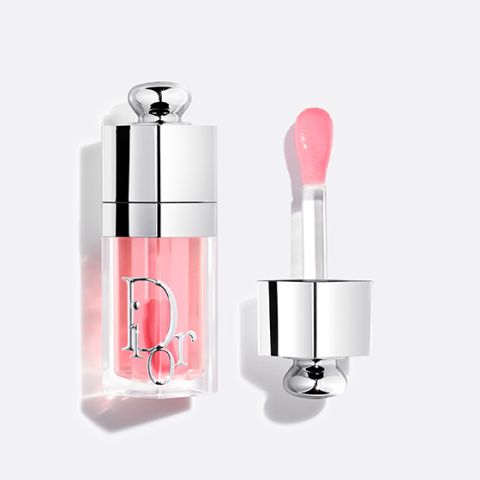 Eine Dior-Lipgloss-Tube mit rosafarbenem Glanz und einer silbernen Kappe, offen dargestellt mit dem Applikatorstab daneben auf weißem Hintergrund.