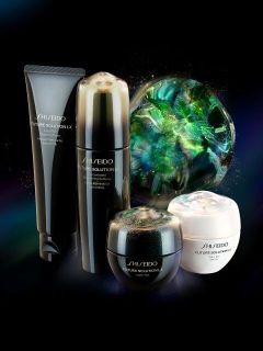 Vier Hautpflegeprodukte der Serie „Shiseido Future Solution LX“ sind vor einem schwarzen Hintergrund abgebildet, hinter ihnen befindet sich eine leuchtende, mehrfarbige Zierkugel.