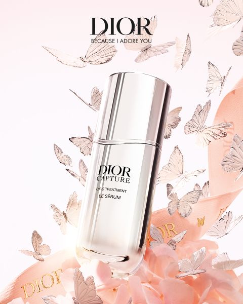 Ein Flakon von Dior Capture Le Sérum, umgeben von rosafarbenen Blütenblättern und zarten Schmetterlingen, darüber das Dior-Logo und der Slogan "Because I Adore You".