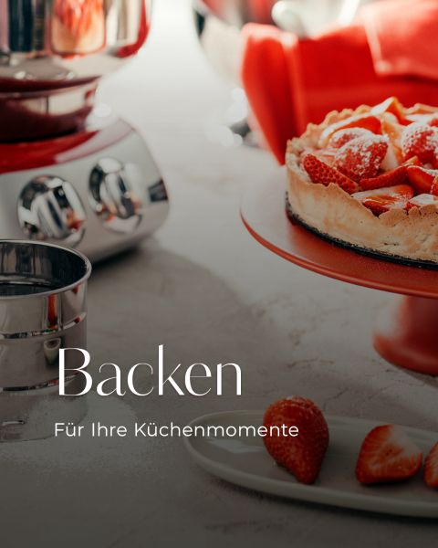 Ein Erdbeerkuchen auf einem roten Ständer, ein Mixer und Backwerkzeuge auf einem Küchentisch. Text: "Backen für Ihre Küchenmomente.