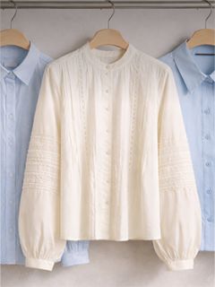 Drei Button-Down-Hemden mit Kragen auf Bügeln, ein weißes strukturiertes Hemd in der Mitte und zwei hellblaue Hemden auf beiden Seiten.