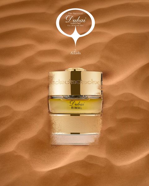 Ein goldener Parfümflakon mit der Aufschrift „Dubai Rimal“ steckt teilweise im glatten Wüstensand, darüber steht der Schriftzug „The Spirit of Dubai“.
