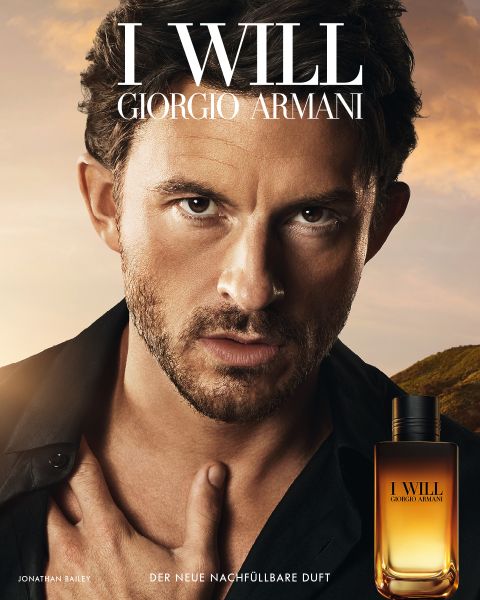 Ein Mann mit kurzen Haaren und Bartstoppeln blickt intensiv in die Kamera und berührt dabei seine Brust. In der rechten unteren Ecke ist ein Parfümflakon von Giorgio Armani zu sehen.