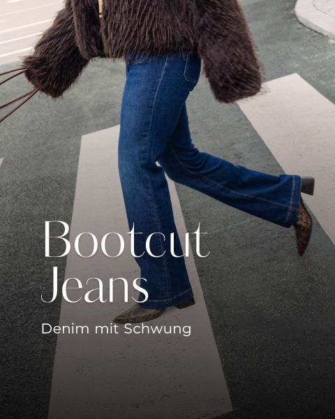 Person crossing a crosswalk in blue bootcut jeans, brown furry jacket, and snakeskin boots; fashion photo.wa