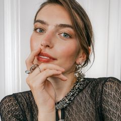 Eine Person, die einen auffälligen silbernen Ring und Creolen trägt.