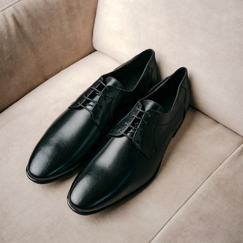 Ein Paar schwarze Leder-Anzugschuhe mit Schnürsenkeln auf einer gepolsterten Sohle.